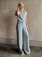 Mature woman wearing the Simple T Top from TWP that is rendered in a light heather grey hemp with short sleeves and boat neckline