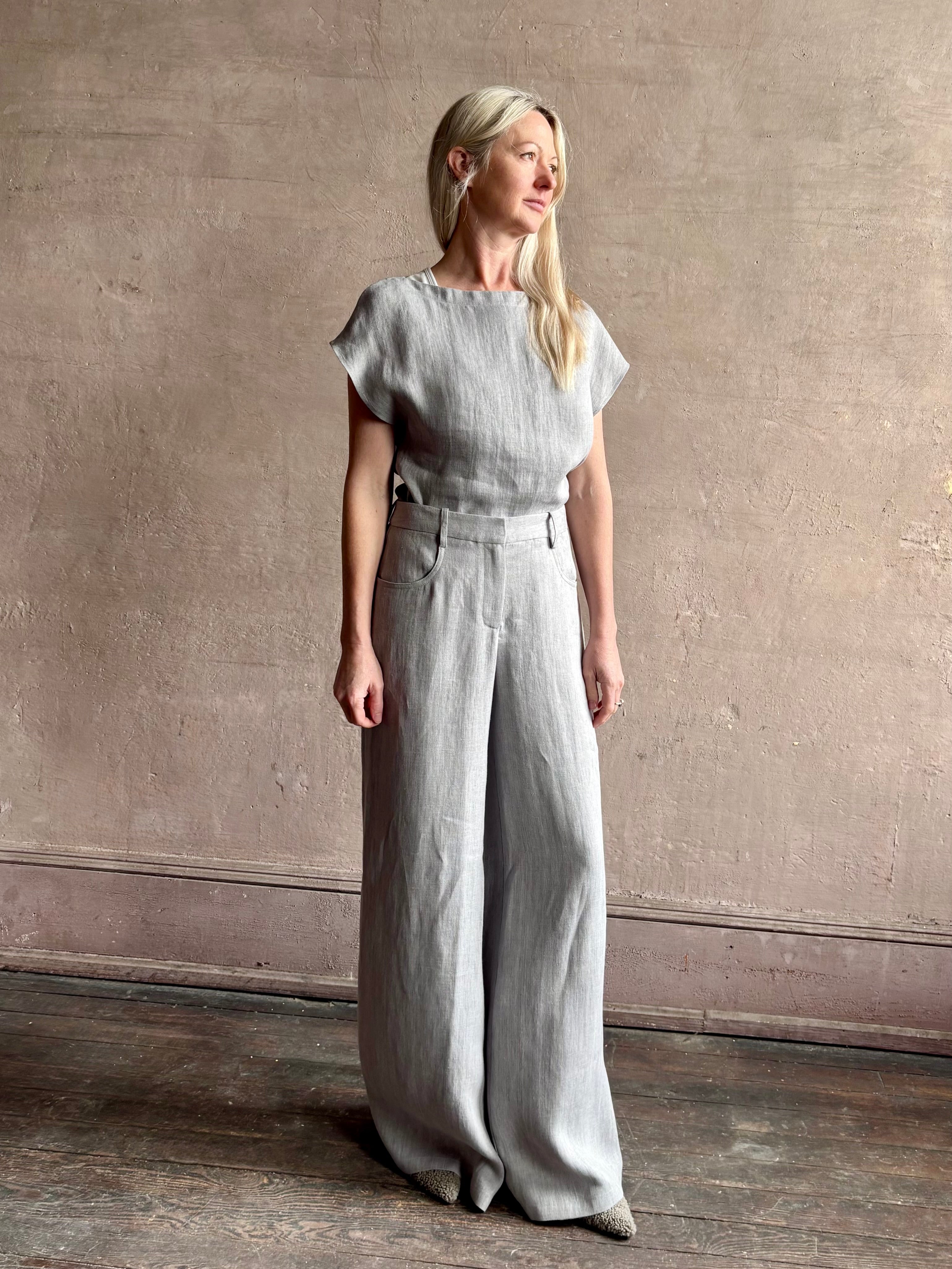 Mature woman wearing the Simple T Top from TWP that is rendered in a light heather grey hemp with short sleeves and boat neckline