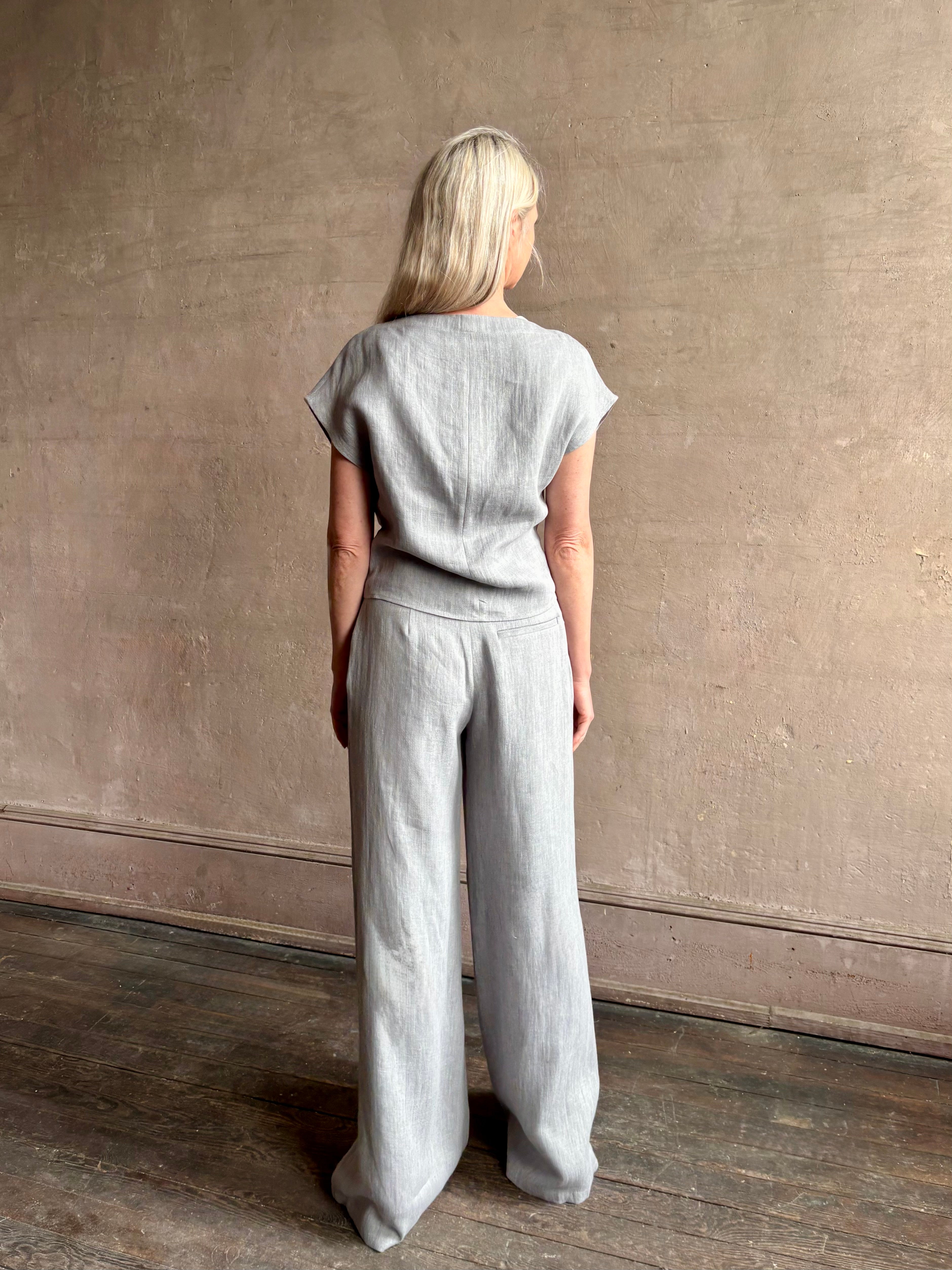 Mature woman wearing the Simple T Top from TWP that is rendered in a light heather grey hemp with short sleeves and boat neckline