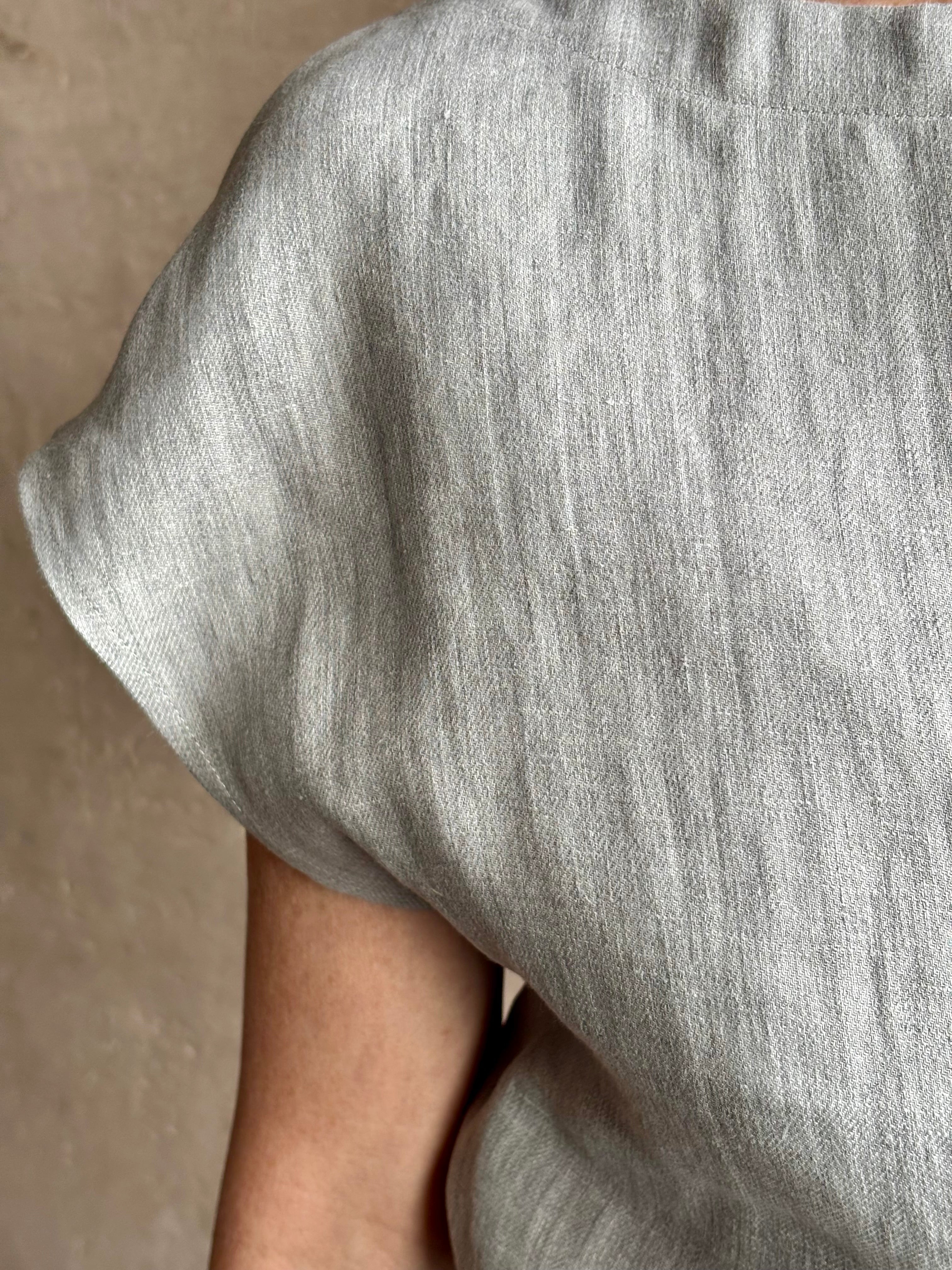 Mature woman wearing the Simple T Top from TWP that is rendered in a light heather grey hemp with short sleeves and boat neckline