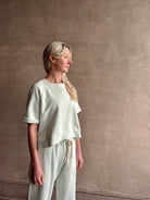Mature woman wearing Slouchy Rolled Tee Top from TWP rendered in a sea glass hue and crafted from cotton with raglan short sleeves, crew neck and relaxed silhouette