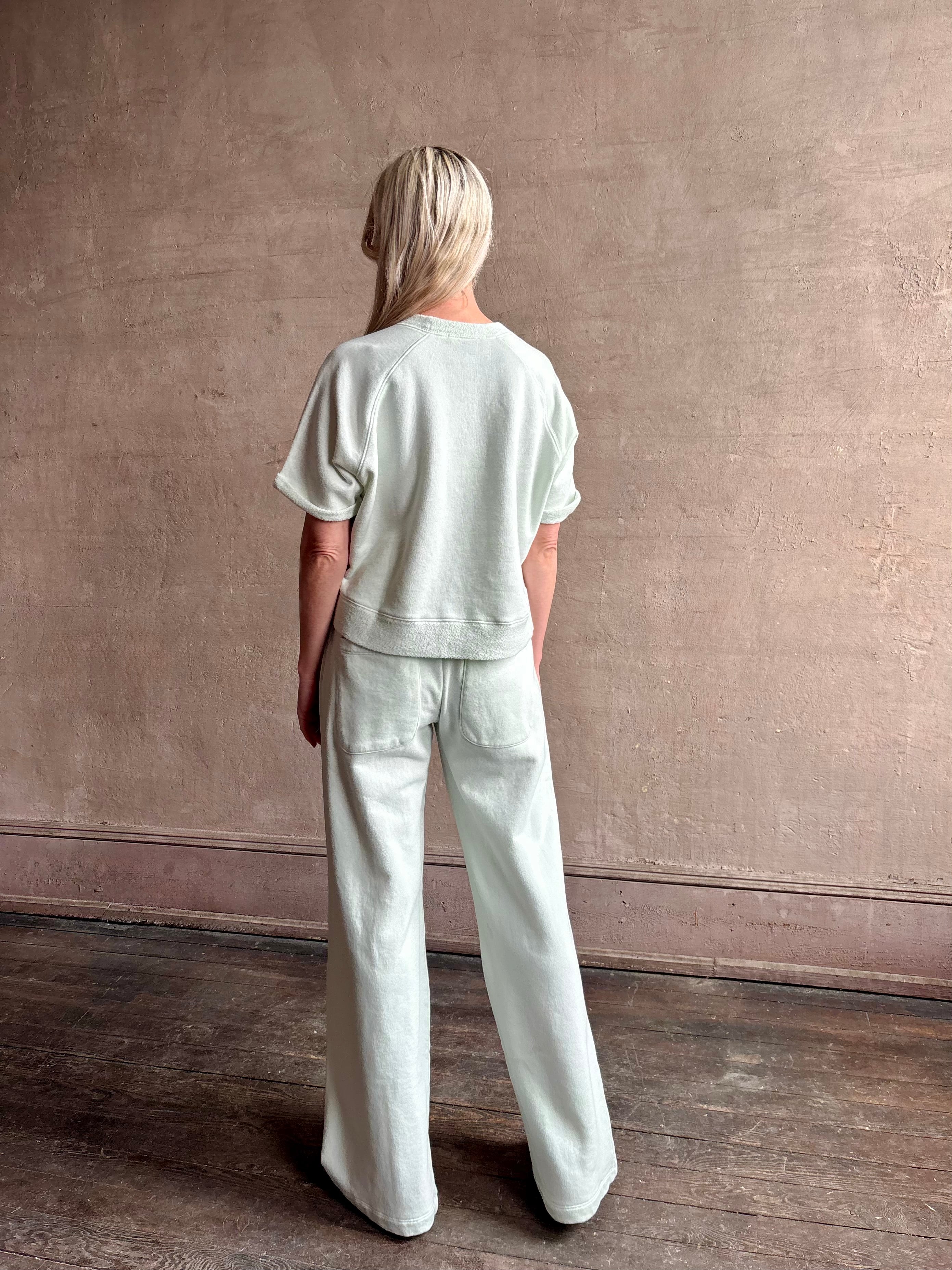 Mature woman wearing Slouchy Rolled Tee Top from TWP rendered in a sea glass hue and crafted from cotton with raglan short sleeves, crew neck and relaxed silhouette