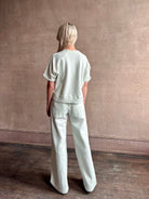 Mature woman wearing Slouchy Rolled Tee Top from TWP rendered in a sea glass hue and crafted from cotton with raglan short sleeves, crew neck and relaxed silhouette