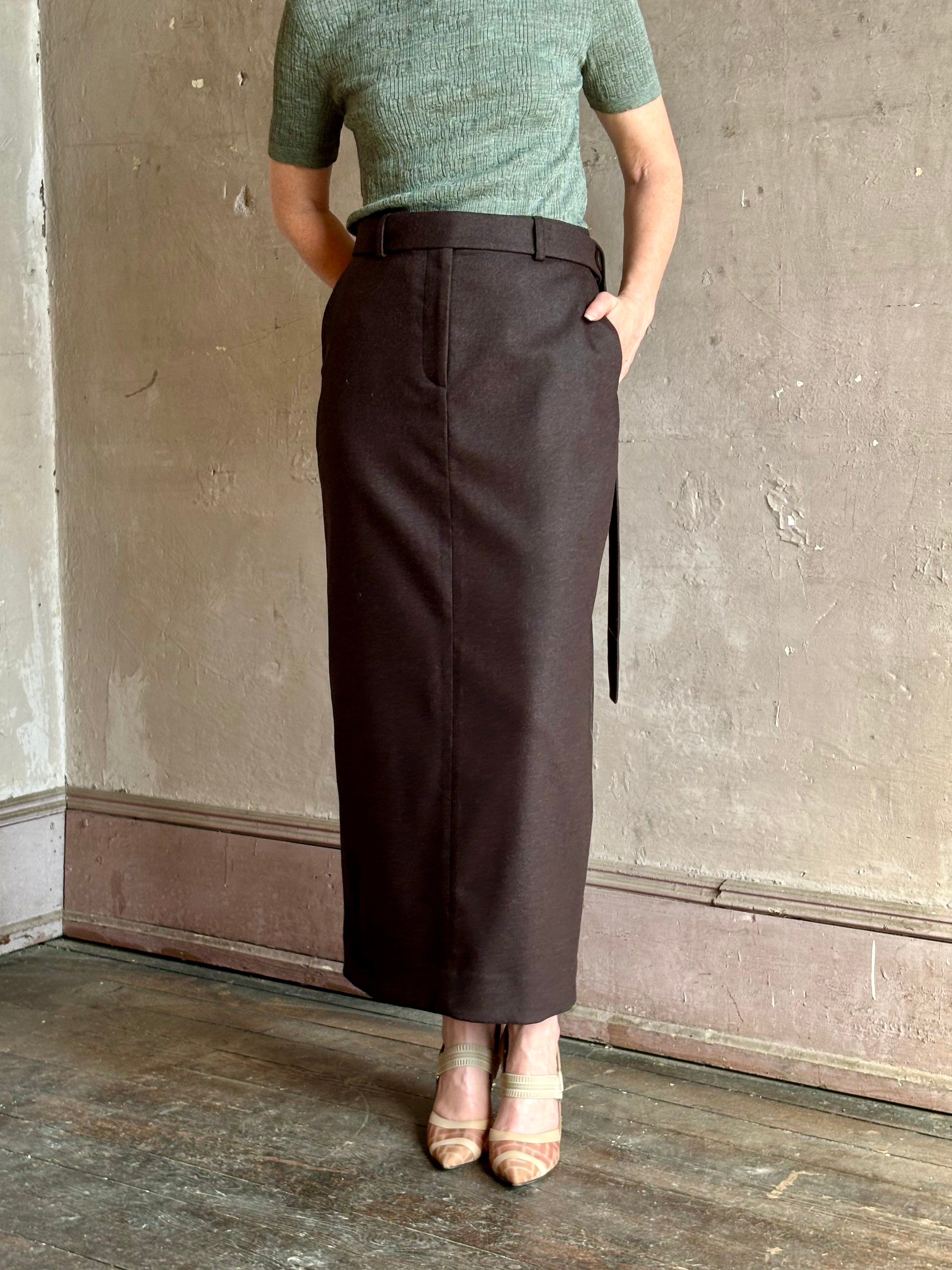 Mature woman wearing a long wool and cashmere chocolate brown pencil skirt from TWP with side pockets, tailored waist and American-made maxi