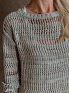 Mature woman wearing Wide Neck Long Sleeve  open knit Sweater from TWP in a luxuriously wearable everyday essential rendered in a soft light grey and crafted from an elevated blend of European flax linen and recycled mulberry silk