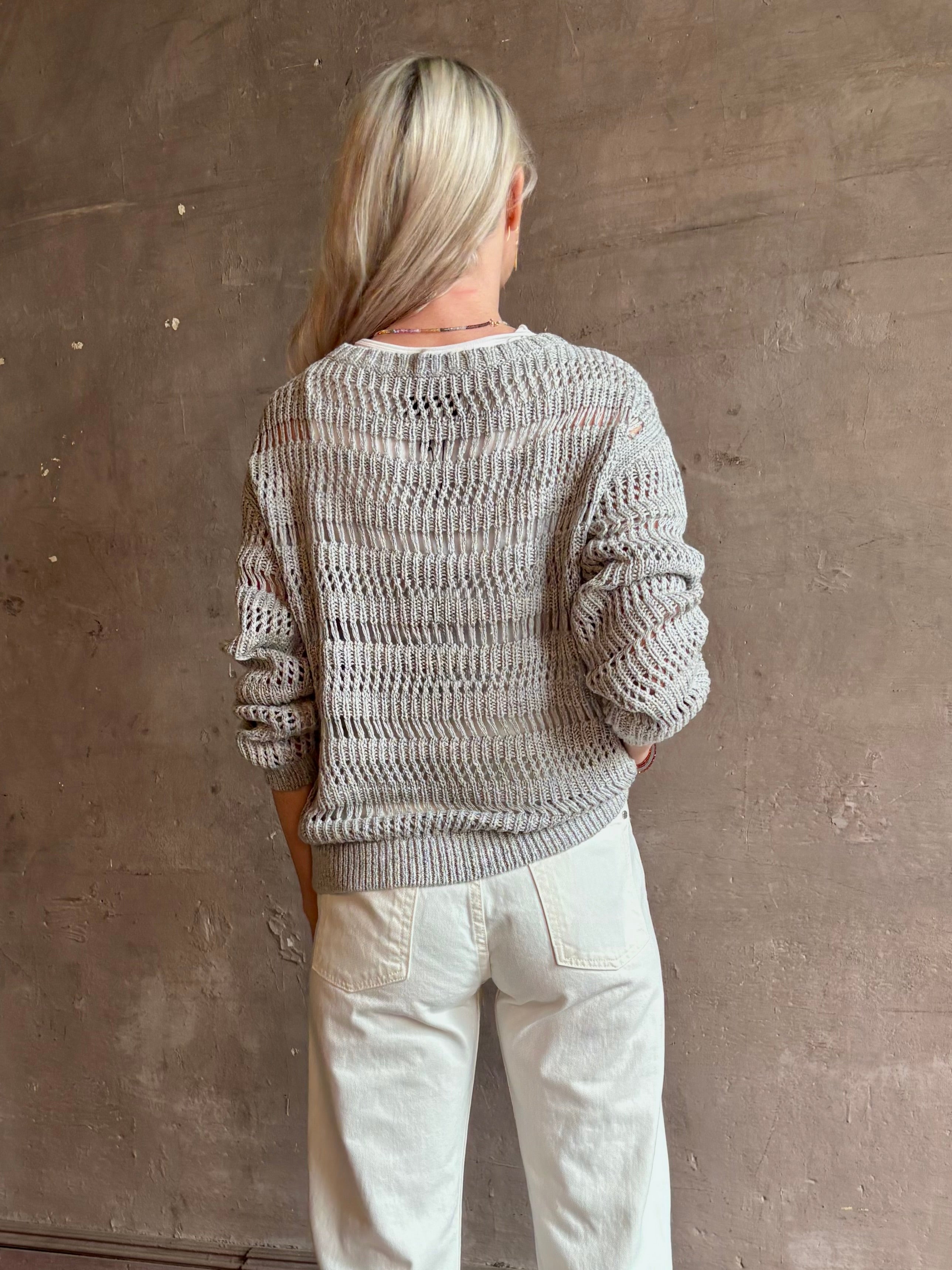 Mature woman wearing Wide Neck Long Sleeve  open knit Sweater from TWP in a luxuriously wearable everyday essential rendered in a soft light grey and crafted from an elevated blend of European flax linen and recycled mulberry silk