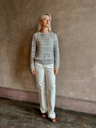 Mature woman wearing Wide Neck Long Sleeve  open knit Sweater from TWP in a luxuriously wearable everyday essential rendered in a soft light grey and crafted from an elevated blend of European flax linen and recycled mulberry silk
