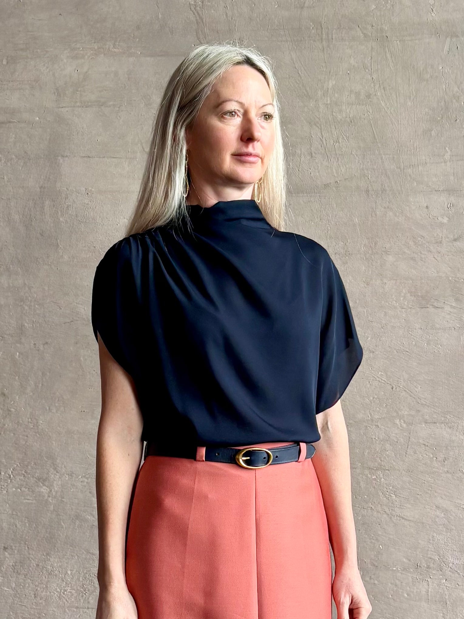 Mature woman wearing an asymmetrical navy blue silk blouse by New York luxury Women's clothing designer TWP with short sleeves 