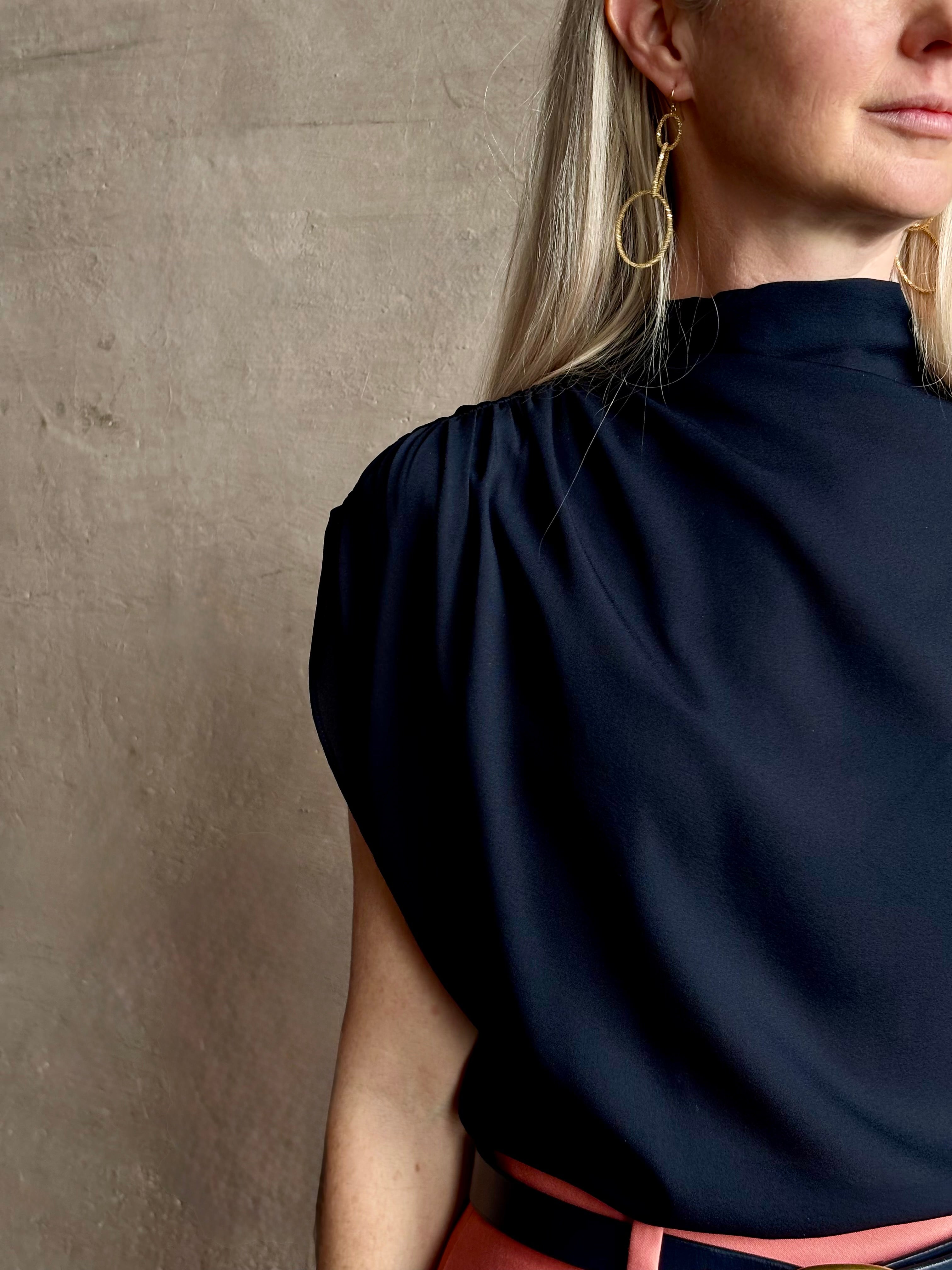 Mature woman wearing an asymmetrical navy blue silk blouse by New York luxury Women's clothing designer TWP with short sleeves