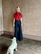 Mature woman wearing Wish You Would blouse from TWP rendered in a rich currant red and crafted from a luxurious silk blend with a mock neck,  asymetrical design and draping short sleeves shoulder button closure