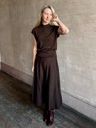 Woman wearing TWP Willow Knit Skirt in chocolate brown premium Merino Wool Knit A-line Skirt and matching top set