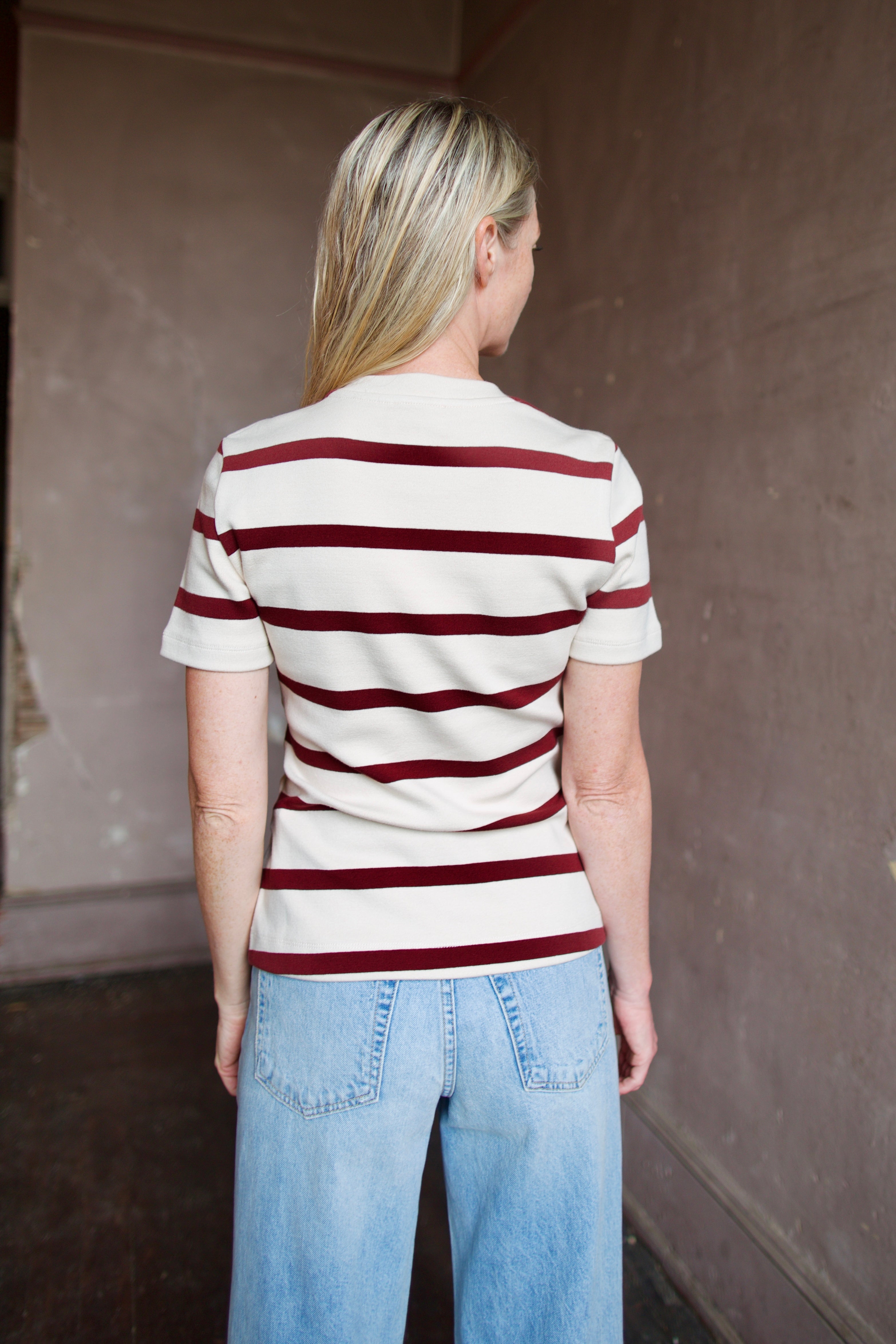 Mature model wearing a flattering striped organic cotton t-shirt from Tanya Taylor with twist front