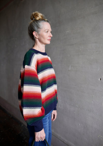 Image featuring a woman wearing the Bubble pullover sweater by The Great with a crew neckline, boxy fit, and drop shoulder in a navy, green, red, and cream stripe.