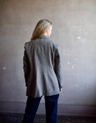 Image featuring a woman wearing the double breasted blazer by The Great with a slightly tailored fit in a versatile heathered black, grey, and brown fabric.