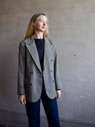 Image featuring a woman wearing the double breasted blazer by The Great with a slightly tailored fit in a versatile heathered black, grey, and brown fabric.