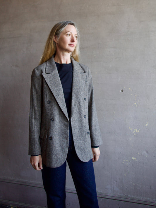 Image featuring a woman wearing the double breasted blazer by The Great with a slightly tailored fit in a versatile heathered black, grey, and brown fabric.