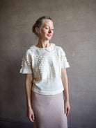 Image featuring a woman wearing the Rosebud top by The Great with a peter pan collar, ruffle lace detailing and a slightly tailored fit in cream color.