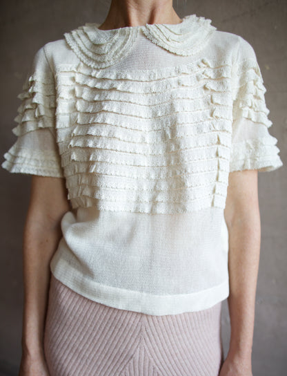 Image featuring a woman wearing the Rosebud top by The Great with a peter pan collar, ruffle lace detailing and a slightly tailored fit in cream color.