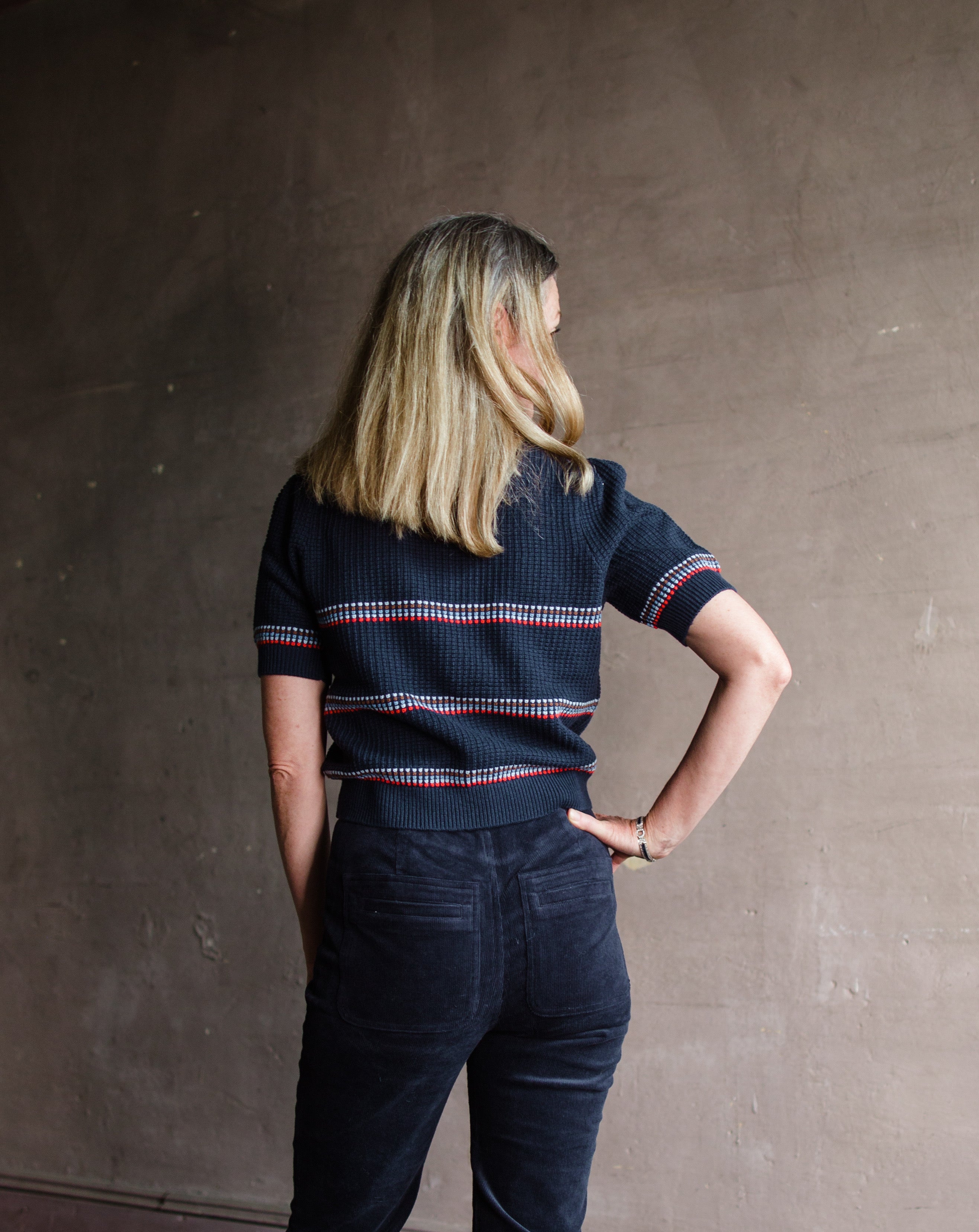 Image featuring a woman wearing the cotton and wool blend short sleeve sweater by The Great with a crew neckline, puff sleeves and a waffle texture in navy blue stripe.