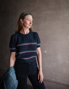 Image featuring a woman wearing the cotton and wool blend short sleeve sweater by The Great with a crew neckline, puff sleeves and a waffle texture in navy blue stripe.