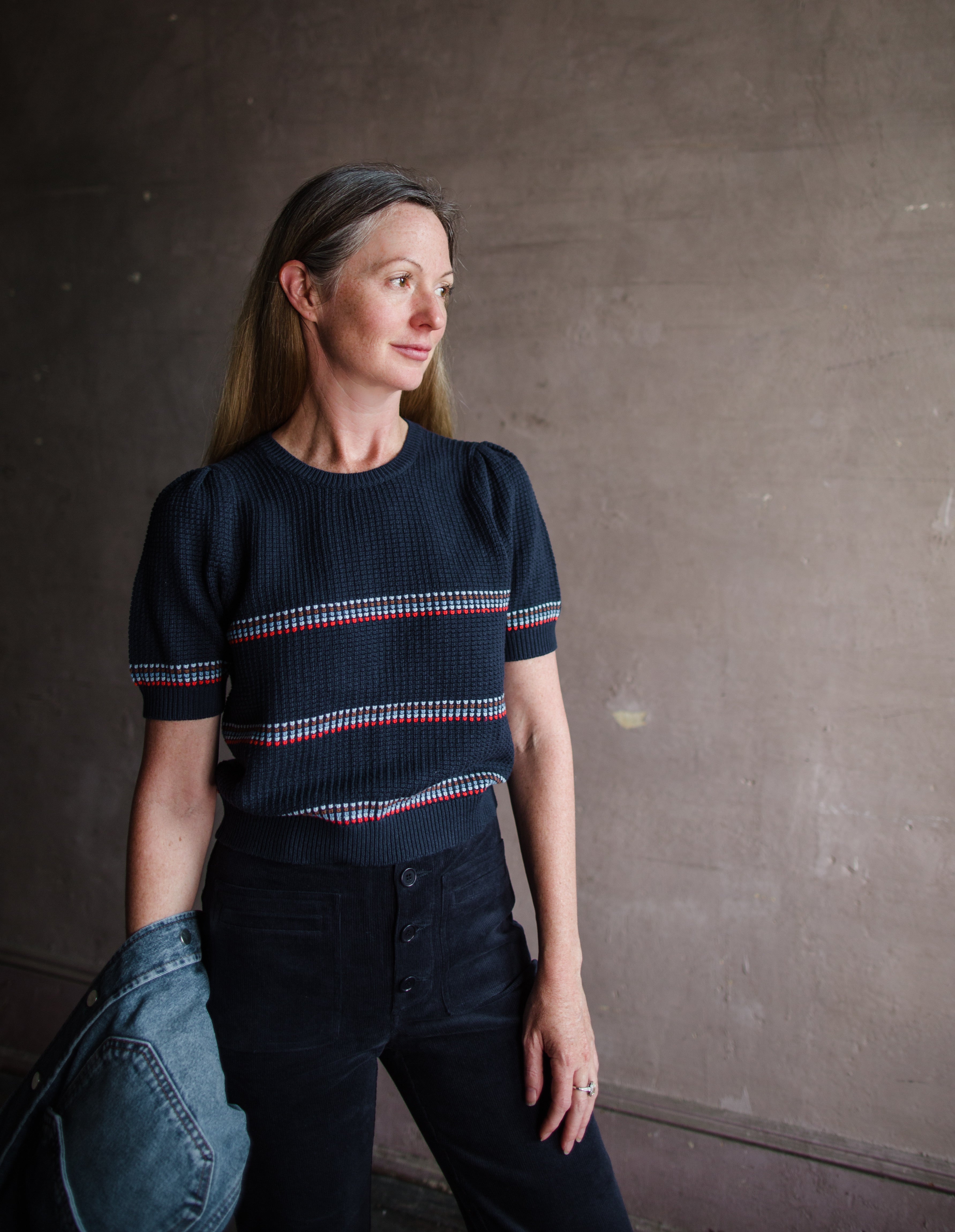 Image featuring a woman wearing the cotton and wool blend short sleeve sweater by The Great with a crew neckline, puff sleeves and a waffle texture in navy blue stripe.