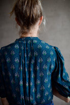 Image featuring a woman wearing the Dakota blouse by Trovata with a v-neck button front, elbow length sleeve in navy with pink and green flower blockprint.