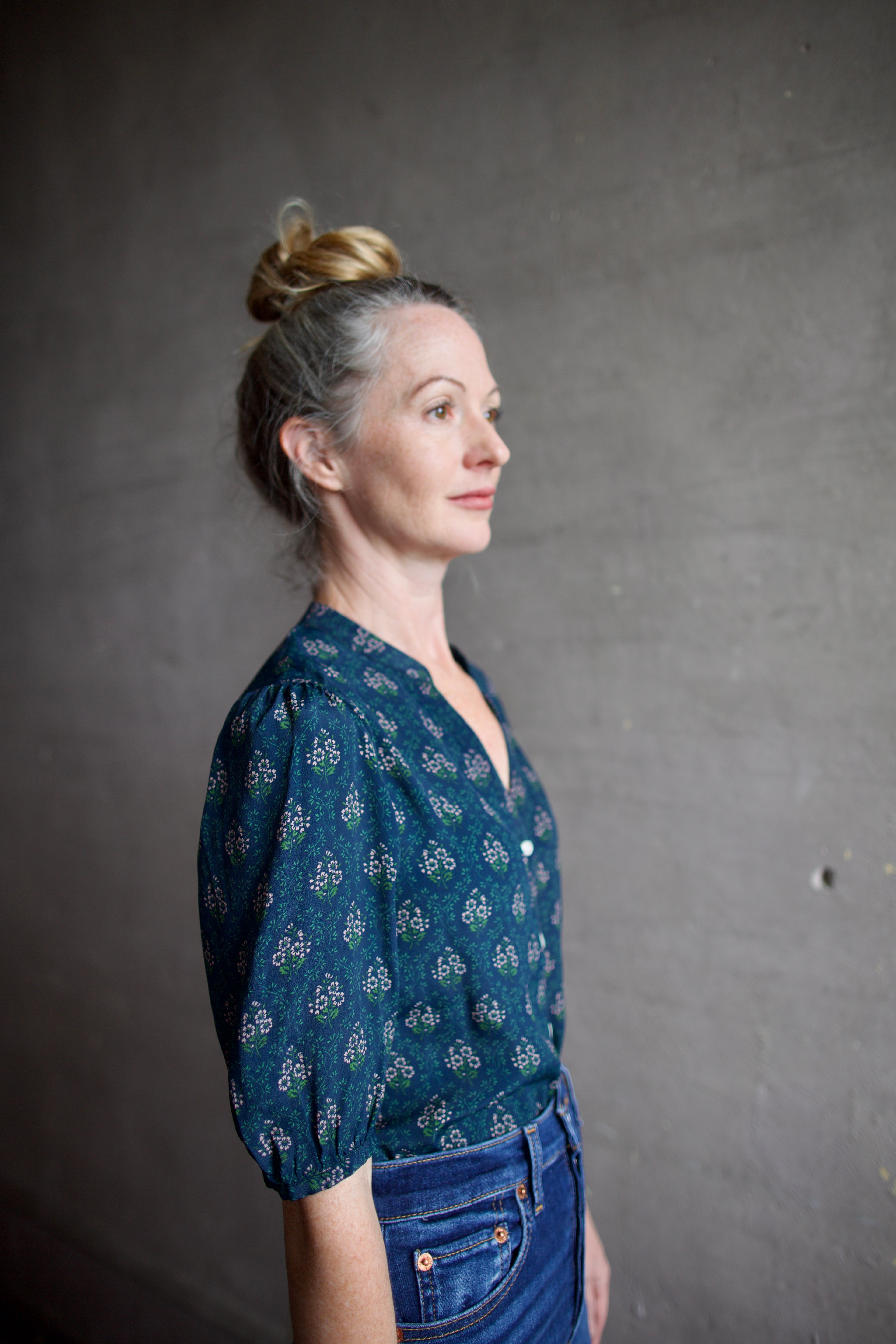 Image featuring a woman wearing the Dakota blouse by Trovata with a v-neck button front, elbow length sleeve in navy with pink and green flower blockprint.