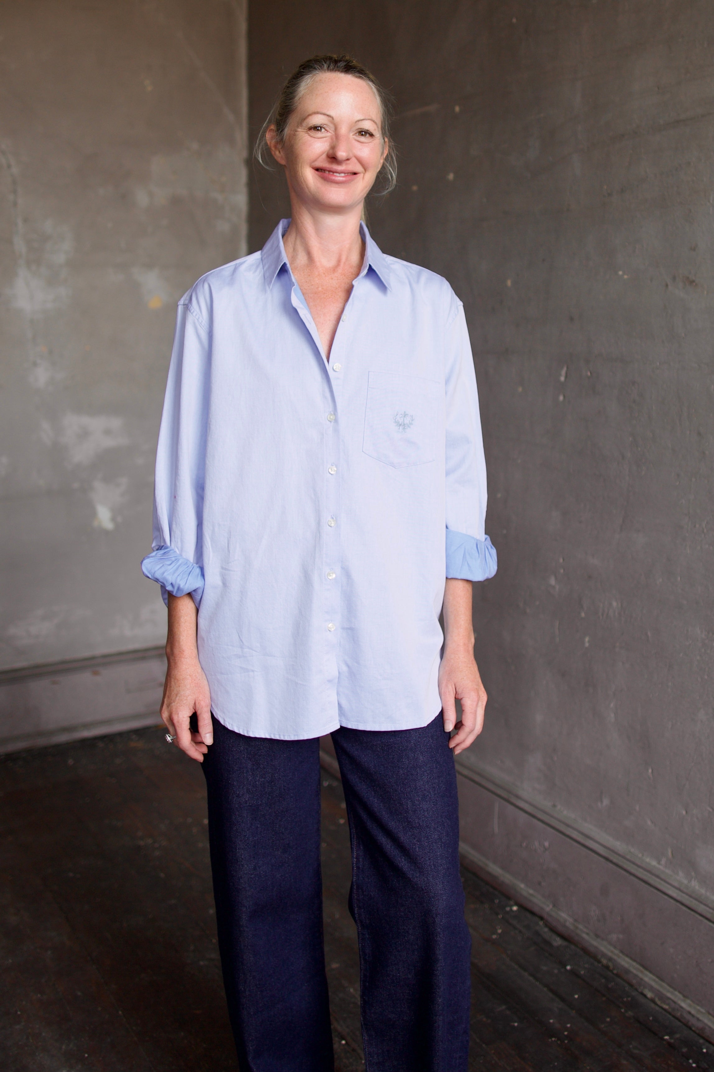 Image of model wearing the Blake light blue button-up shirt with a small embroidered design by Trovata