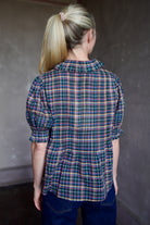 Model wearing Trovata Jess Blouse in cotton plaid with ruffle short sleeve detail pin tucking button front