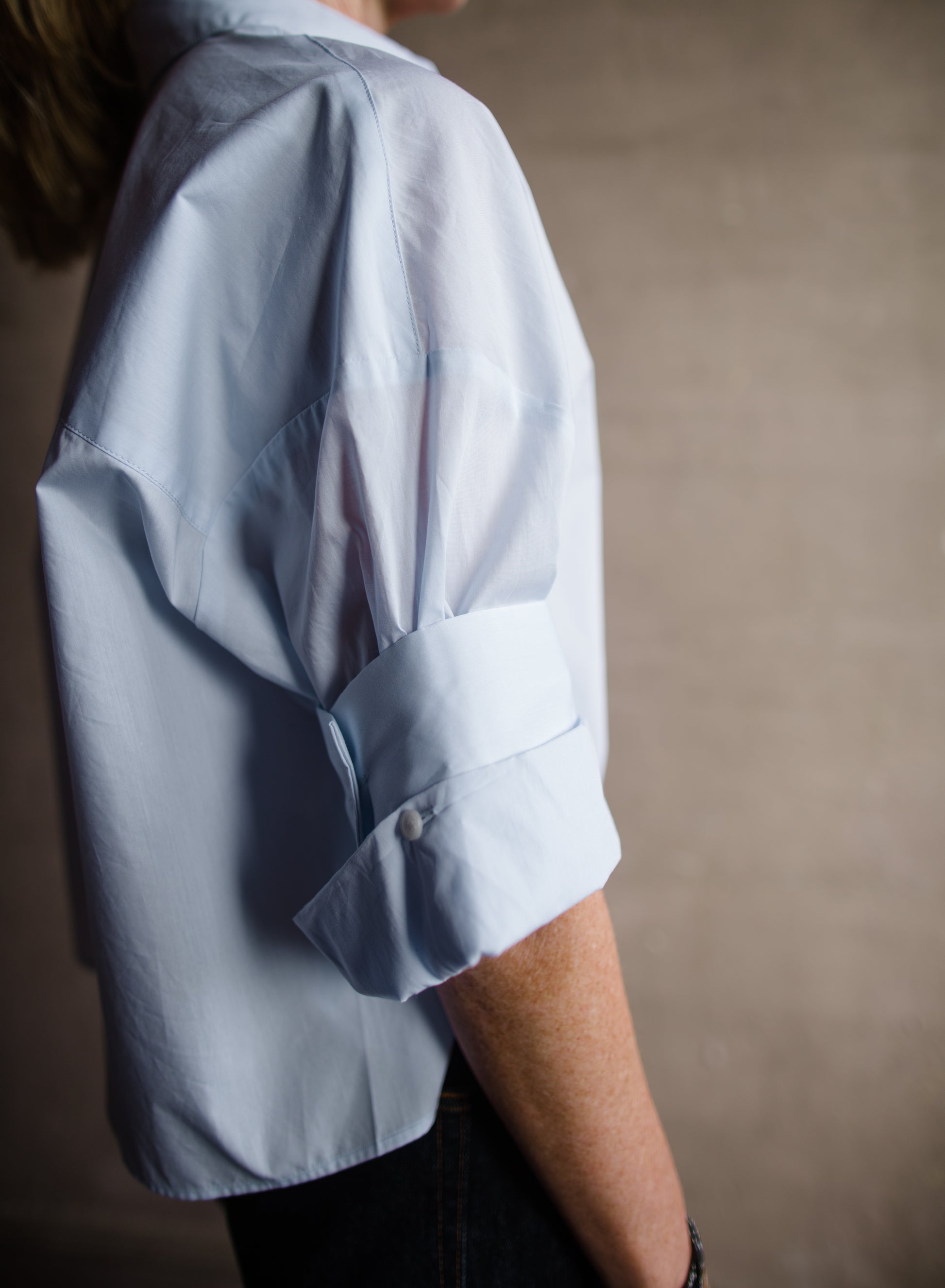 Image featuring a woman wearing TWP next ex shirt in baby blue color fabricated from 100% superfine cotton with rolled and buttoned sleeve detail.