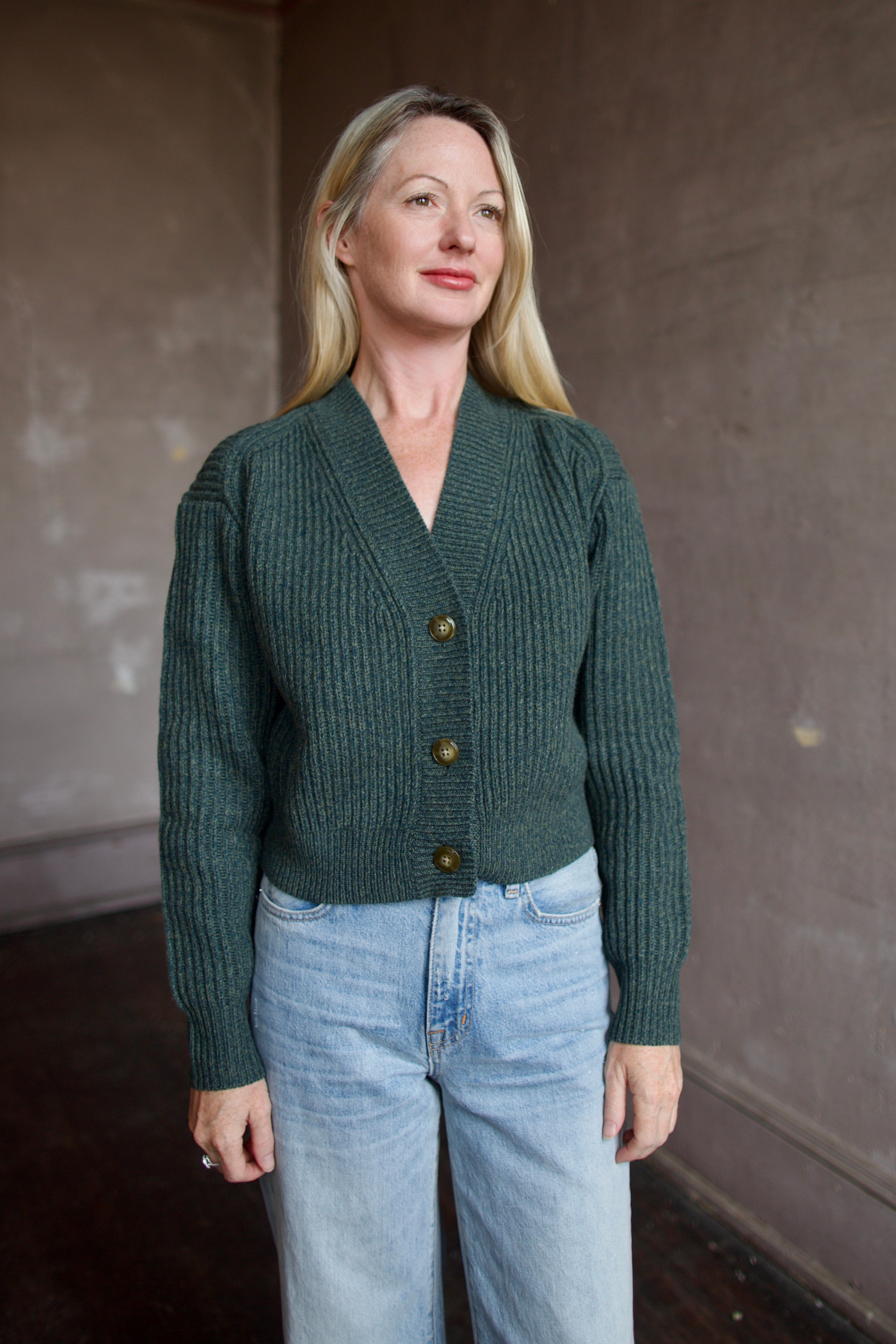 Mature wearing a green button front v neck cashmere cardigan by luxury New York brand TWP