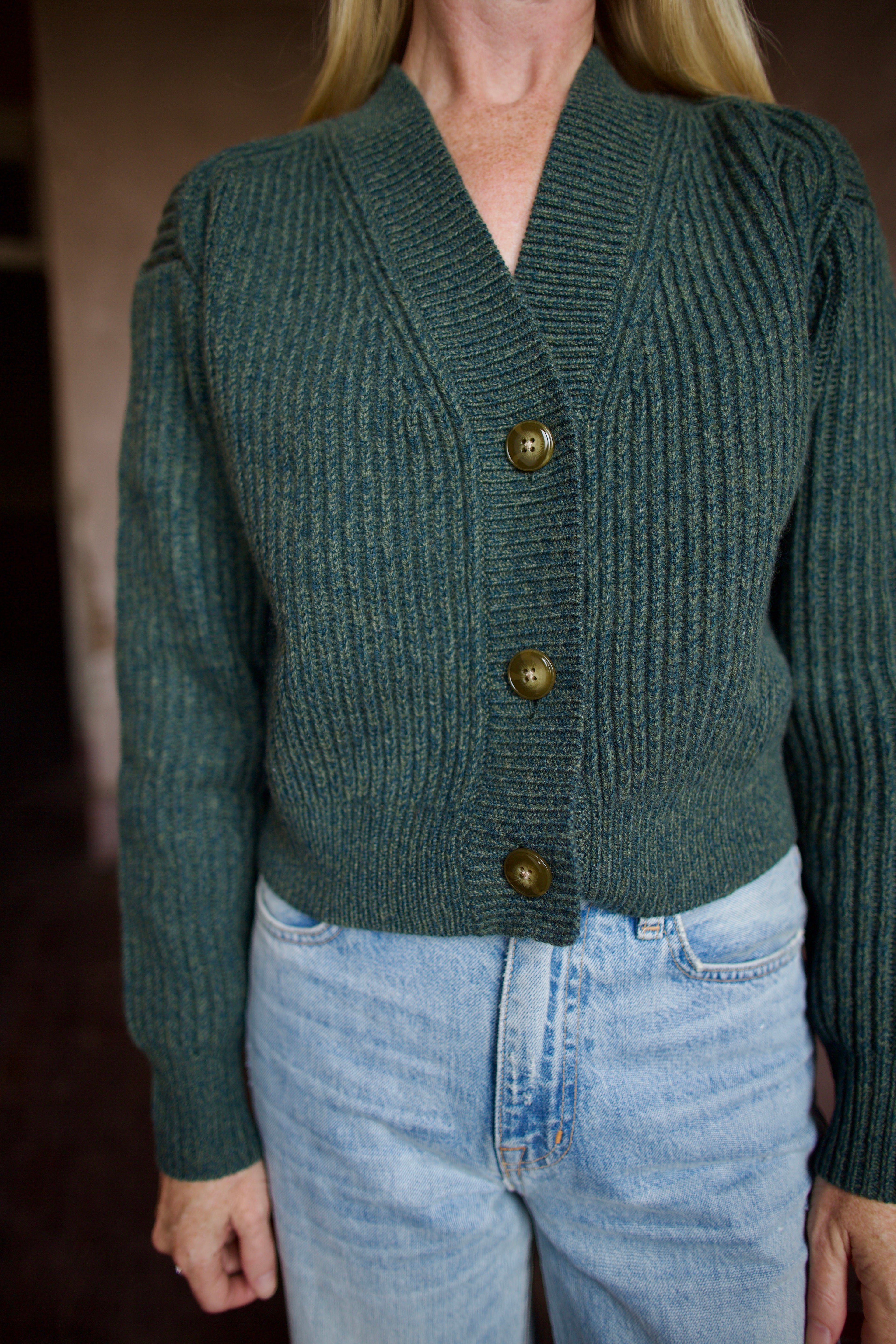 Mature woman wearing TWP Cropped Cardigan in Duffle Bag green ribbed cashmere V-neck long sleeves three button closure