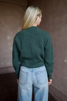 Mature woman wearing TWP Cropped Cardigan in Duffle Bag green ribbed cashmere V-neck long sleeves three button closure