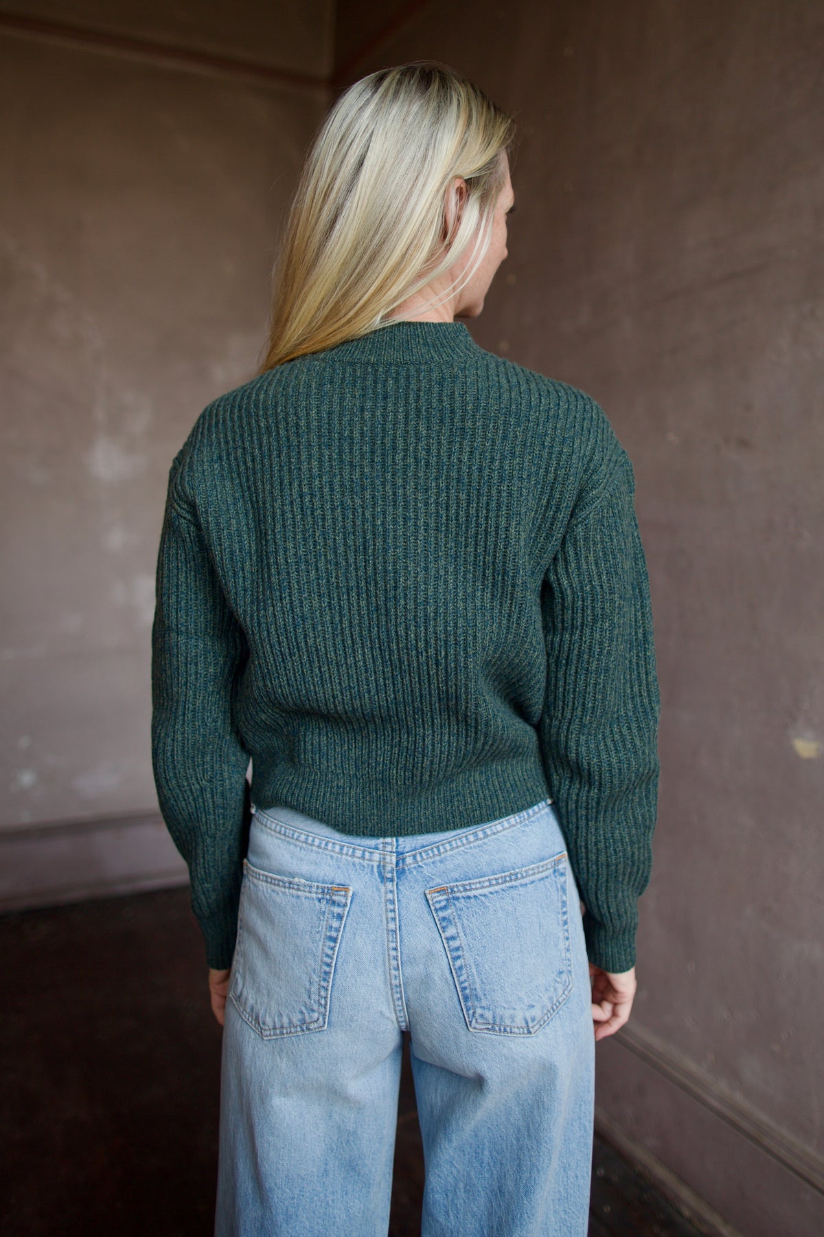 Mature woman wearing TWP Cropped Cardigan in Duffle Bag green ribbed cashmere V-neck long sleeves three button closure