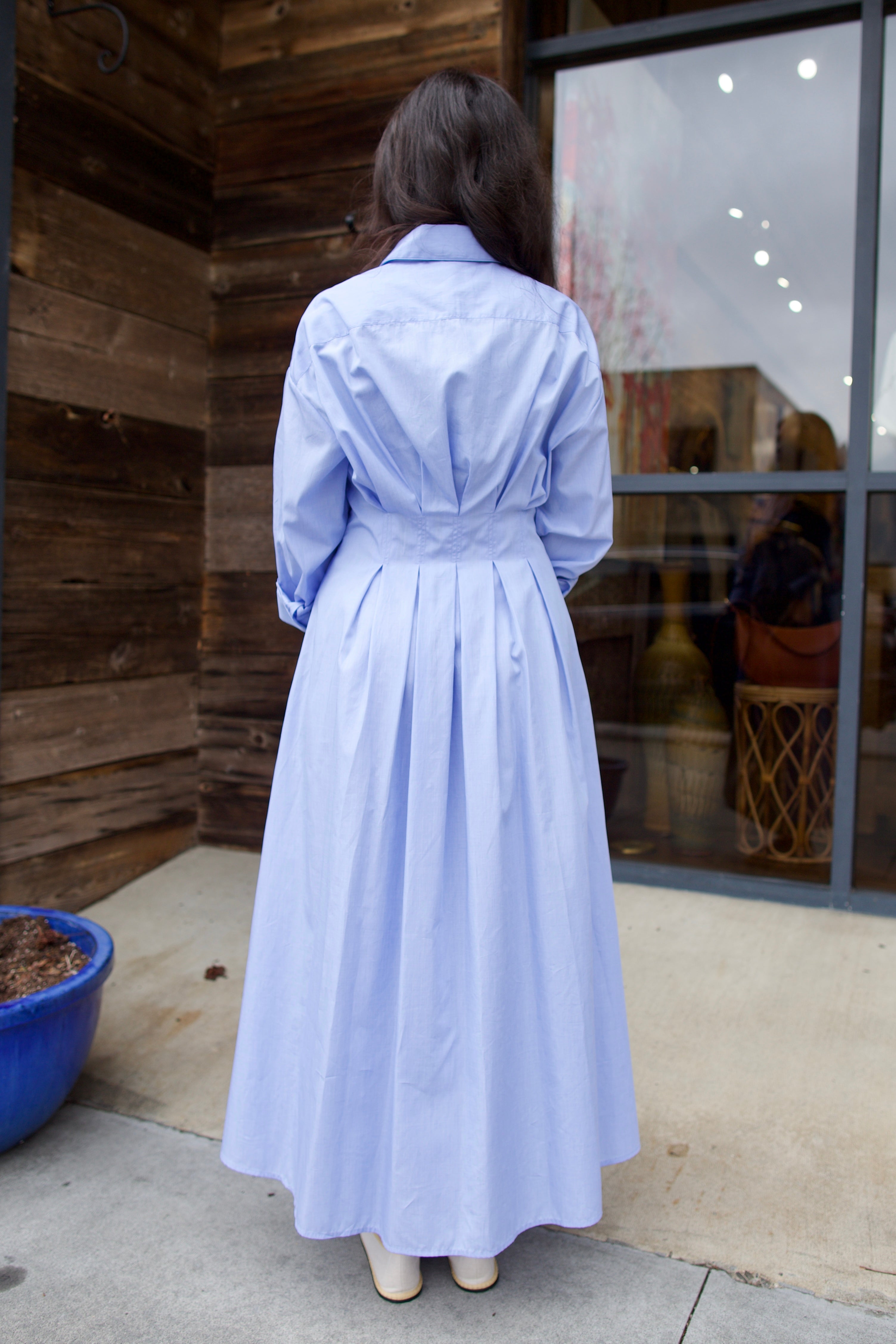 Image of woman wearing TWP M Dress, luxury women's superfine cotton dress featuring button-front closure with pleats and midi hem in blue