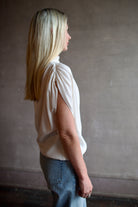 Mature woman wearing an elevated soft blush TWP silk blouse with beautifully draped short sleeves and modern asymmetrical design
