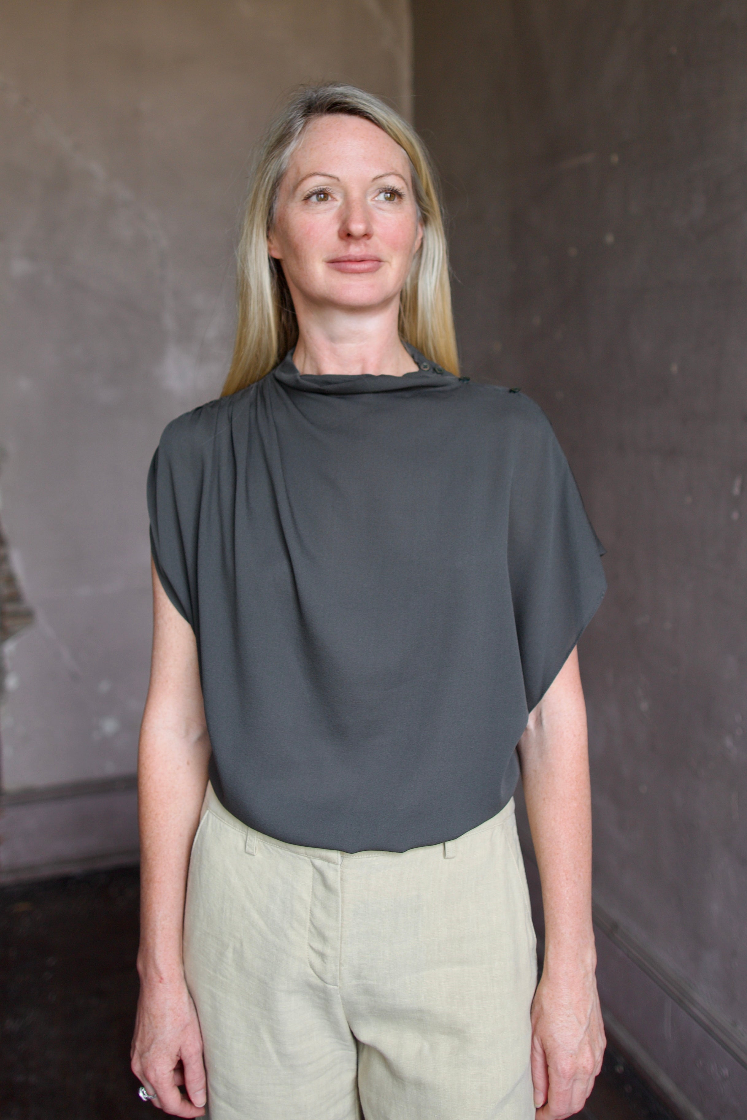 Mature model wearing a rich green TWP silk blouse with waterfall front  and modern asymmetrical design