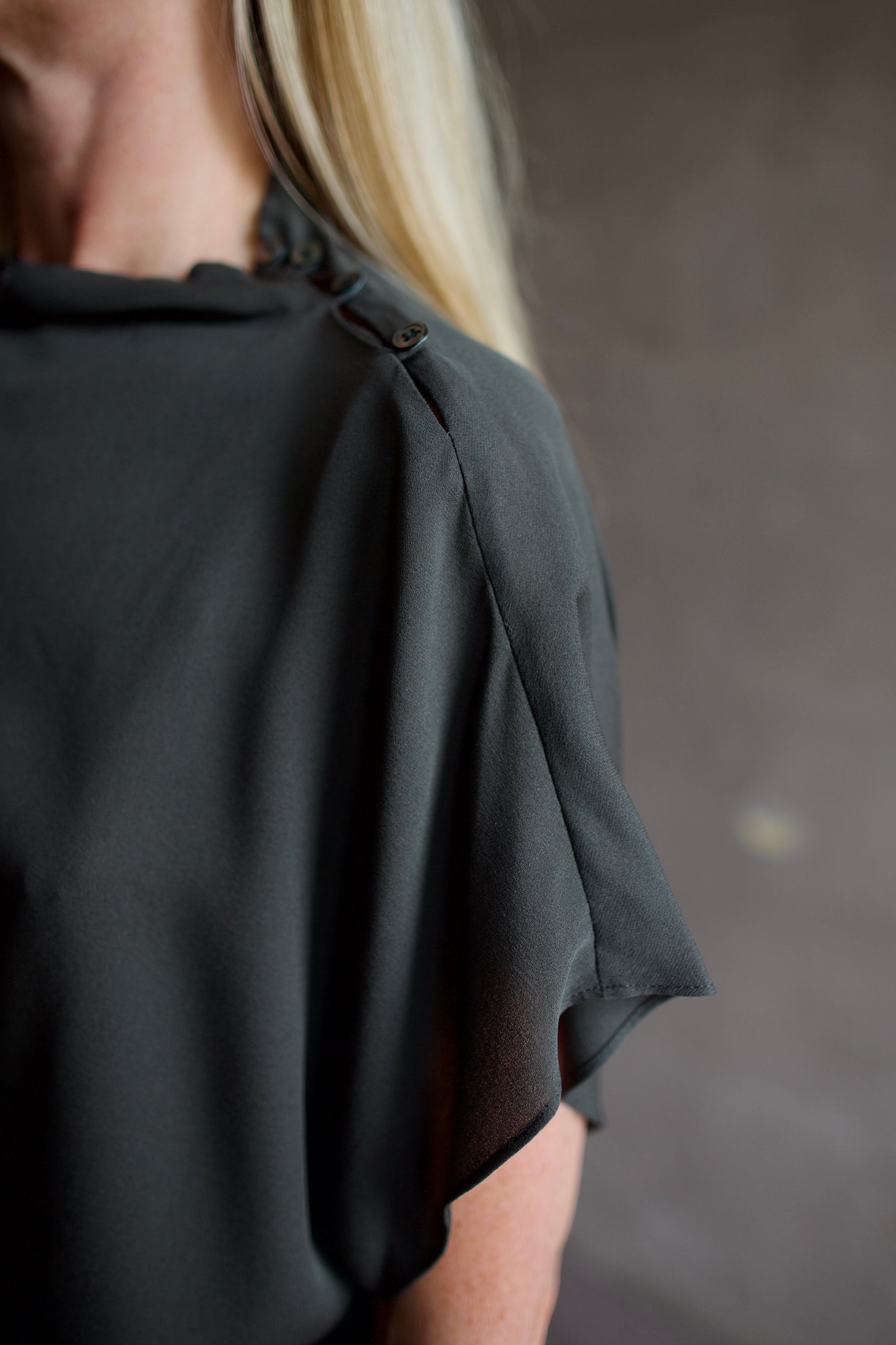 Mature model wearing a rich green TWP silk blouse with waterfall front  and modern asymmetrical design