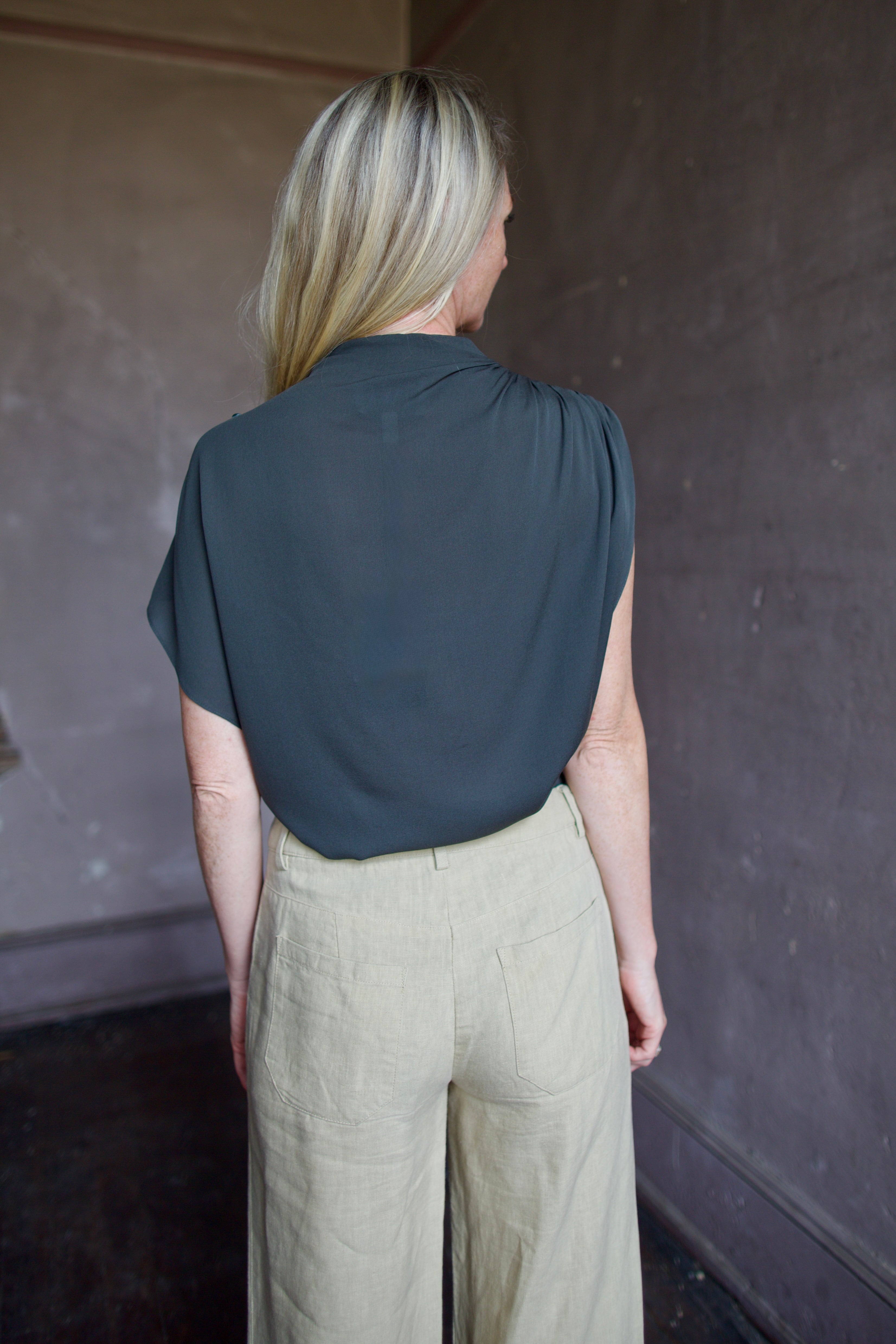 Mature model wearing a rich green TWP silk blouse with waterfall front  and modern asymmetrical design