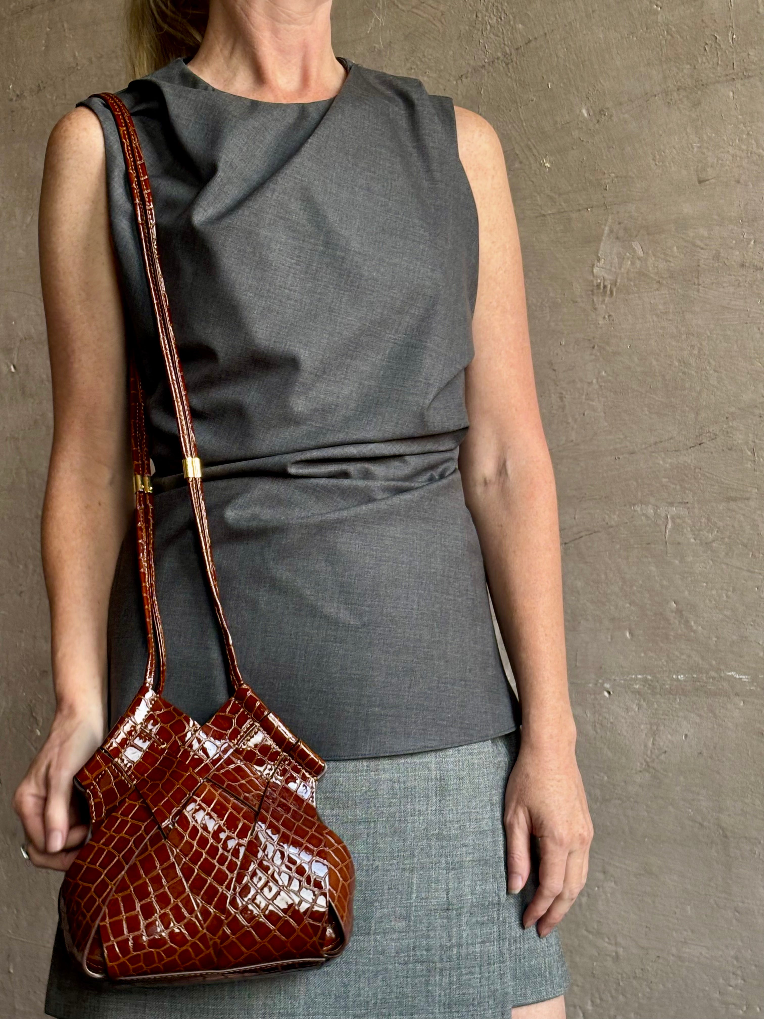 Image of mature model wearing luxury designer ULLA JOHNSON Charlotte Crossbody handbag in Chestnut brown with Crocodile-Embossed leather