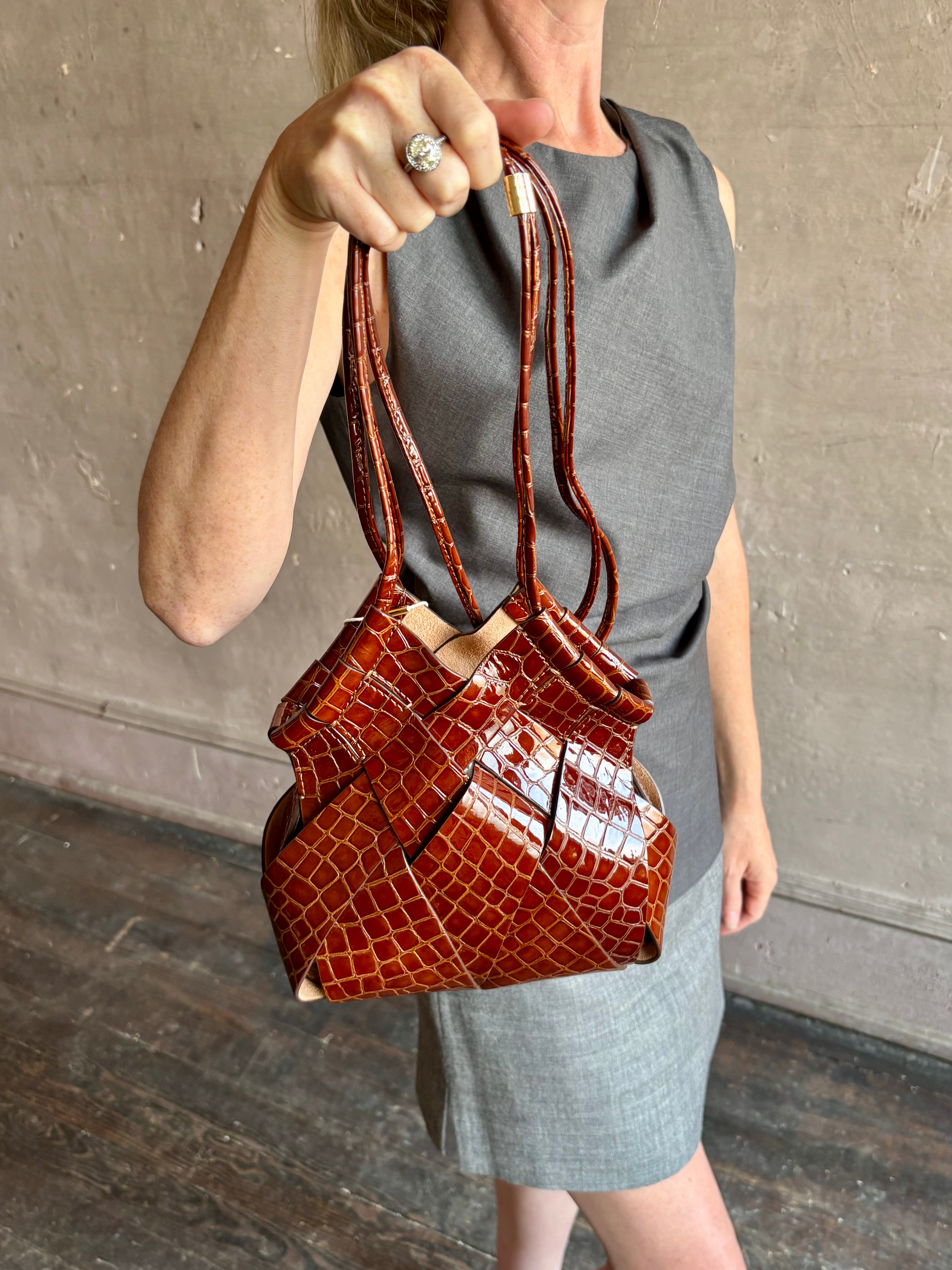 Image of mature model wearing luxury designer ULLA JOHNSON Charlotte Crossbody handbag in Chestnut brown with Crocodile-Embossed leather