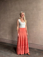 Woman wearing the feminine  Annisa Eyelet Knit A-line maxi skirt from Ulla Johnson rendered in a luminous coral hue and crafted from luxury knit 
