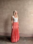 Woman wearing the feminine  Annisa Eyelet Knit A-line maxi skirt from Ulla Johnson rendered in a luminous coral hue and crafted from luxury knit with matching top