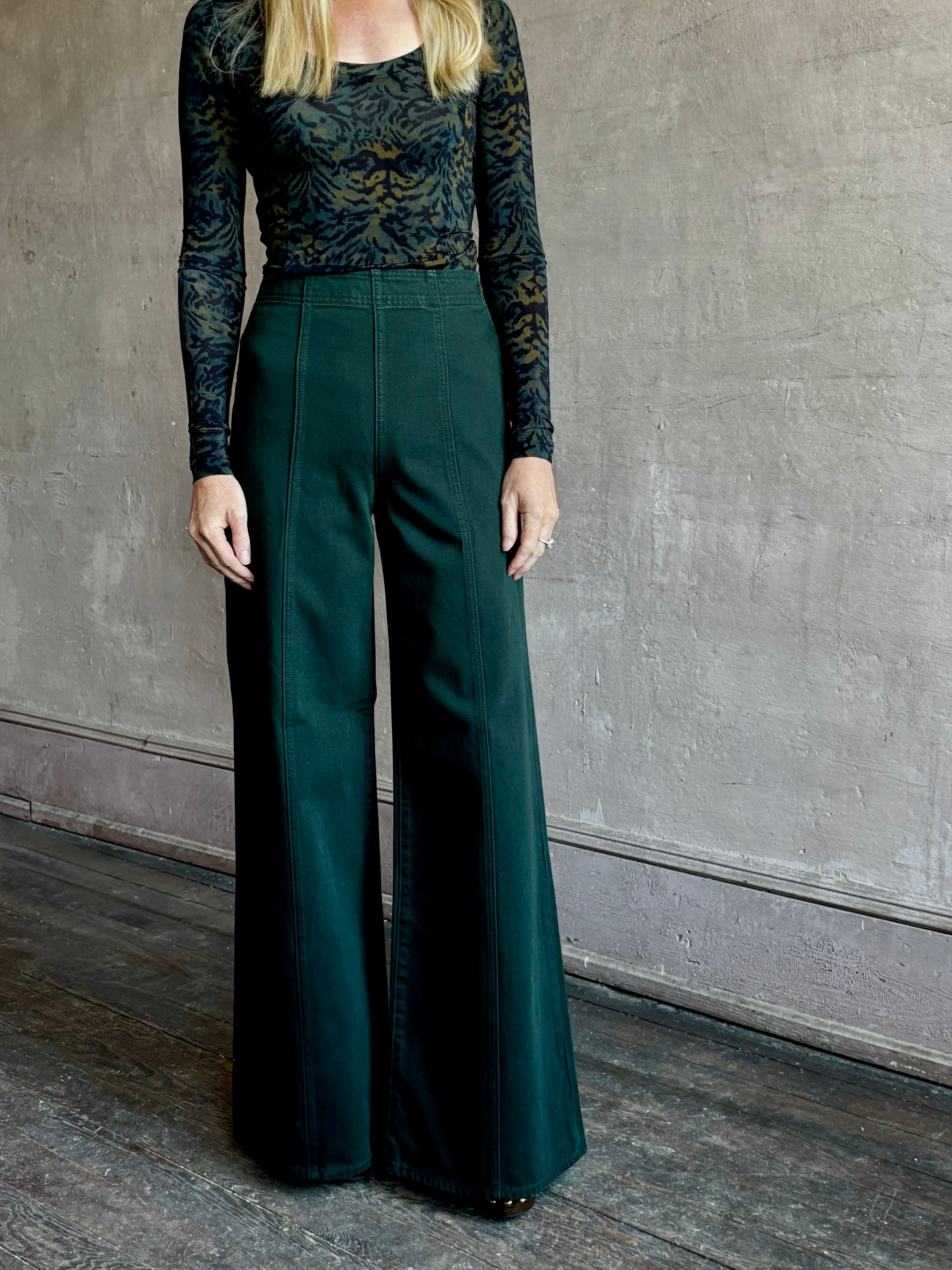 Image of woman wearing made in the USA luxury Ulla Johnson Bianca dark green denim with flat front wide leg and front seam details