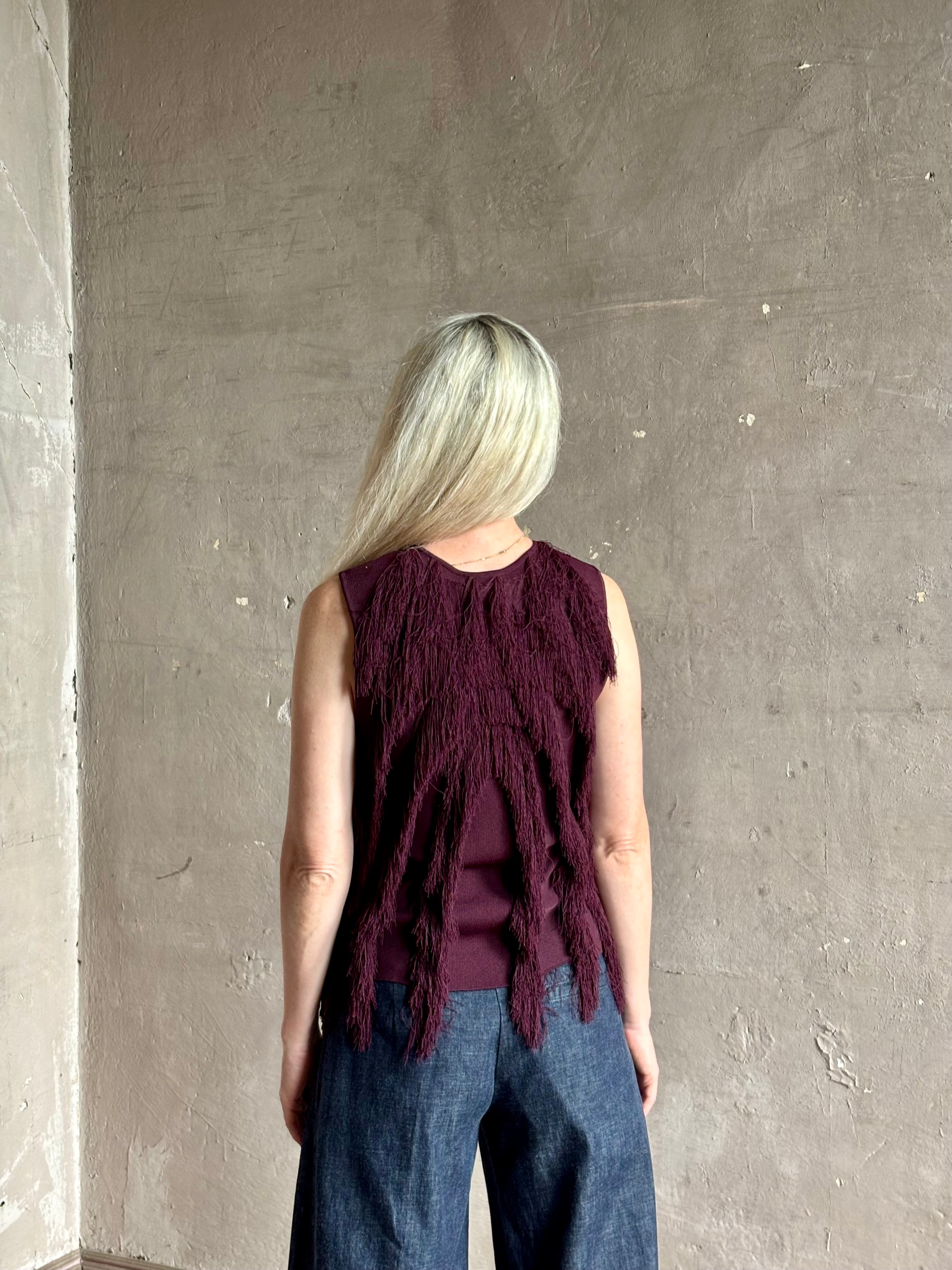 Mature woman wearing sleeveless Ulla Johnson burgundy finge knit top with fun movement in an elevated viscose blend