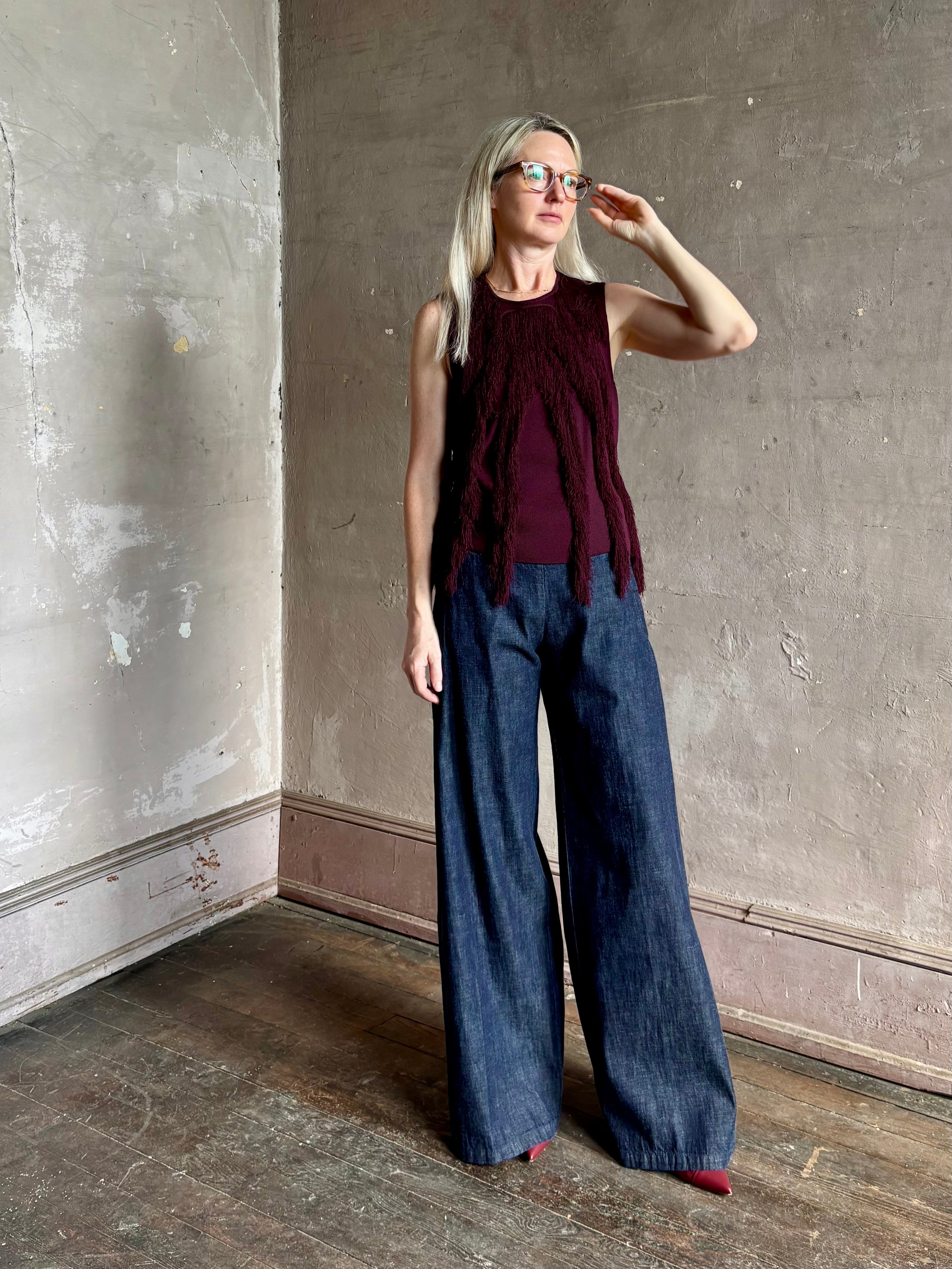 Mature woman wearing sleeveless Ulla Johnson burgundy finge knit top with fun movement in an elevated viscose blend