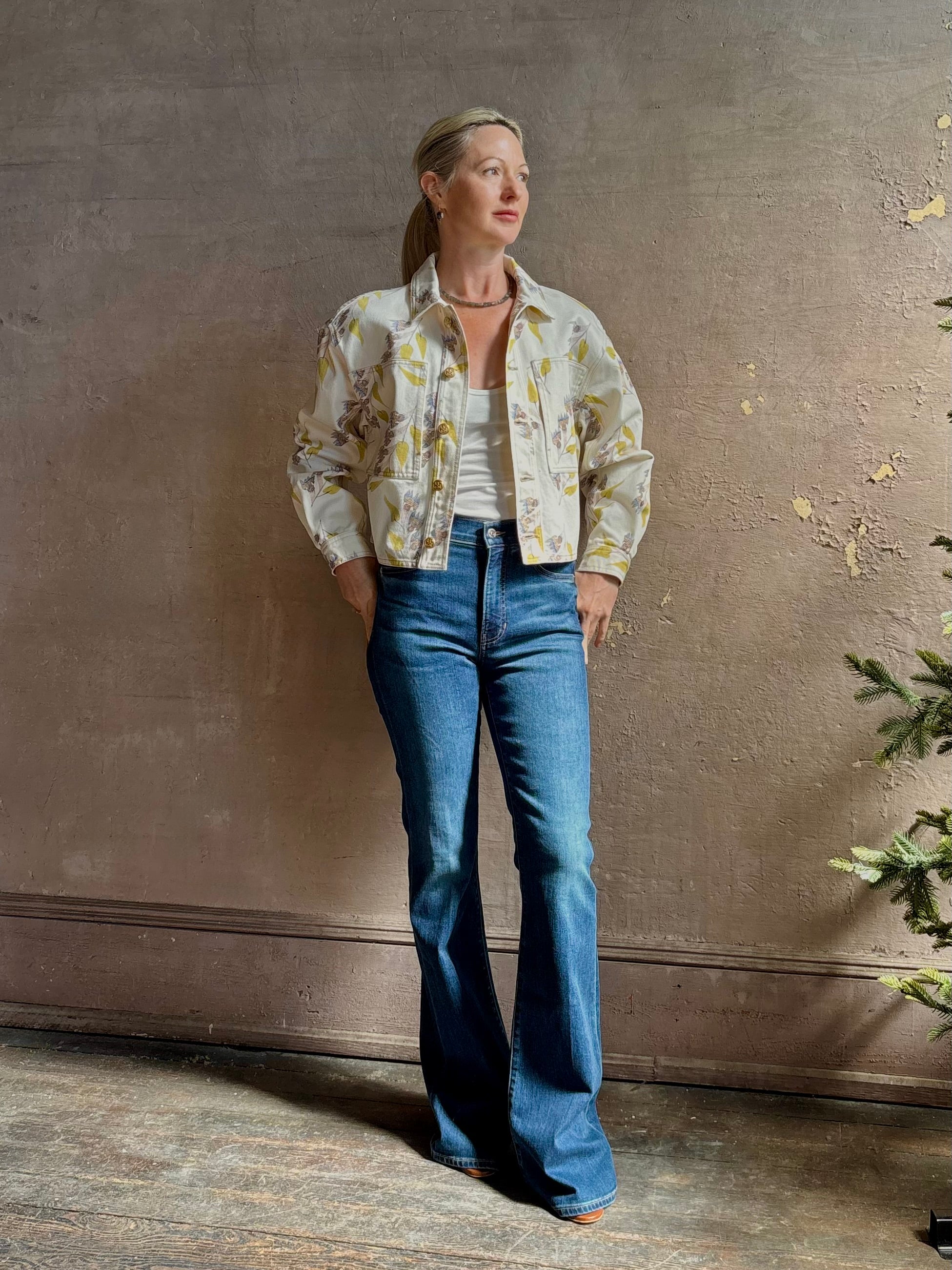 Mature woman wearing designer ULLA JOHNSON Bobbi cotton denim Jacket in an artisan collaboration print Infinite Flower with gold buttons, front pockets and crop length cool girl vibe