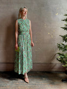 Mature woman wearing  women's designer celestina silk maxi dress rendered in a mint green ground adorned with delicate brown and pink florals from Ulla Johnson that is sleevesless with gathered fabric bodice and waistband