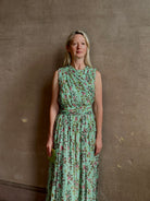 Mature woman wearing  women's designer celestina silk maxi dress rendered in a mint green ground adorned with delicate brown and pink florals from Ulla Johnson that is sleevesless with gathered fabric bodice and waistband