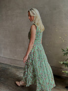 Mature woman wearing  women's designer celestina silk maxi dress rendered in a mint green ground adorned with delicate brown and pink florals from Ulla Johnson that is sleevesless with gathered fabric bodice and waistband